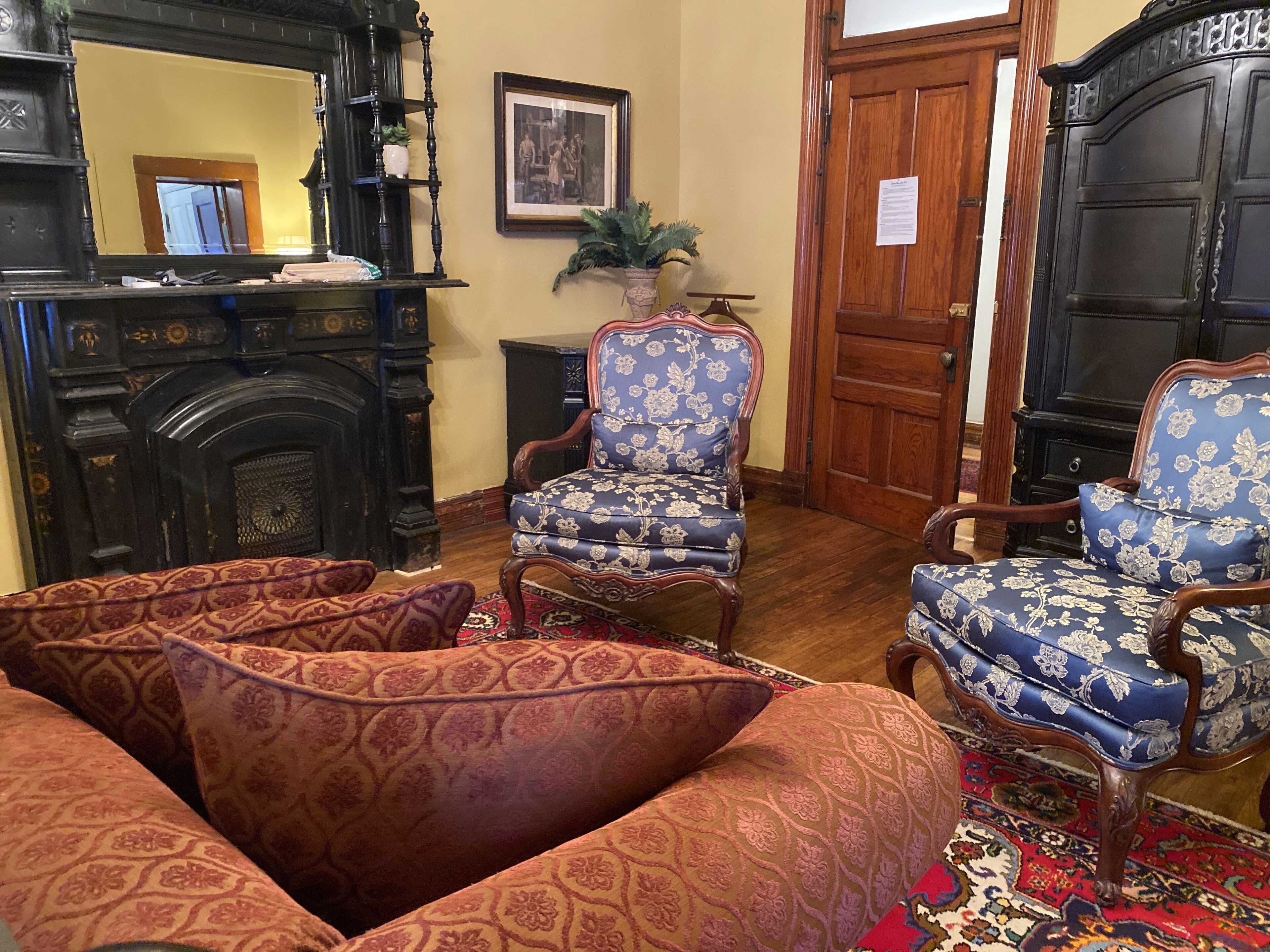 A traditional room with ornate furniture, including a patterned armchair and a sofa with floral upholstery.