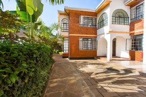 A two-story building with a brick facade, large windows, and a stone pathway leading to the entrance. - Convent International Hotel Nairobi (Nairobi)