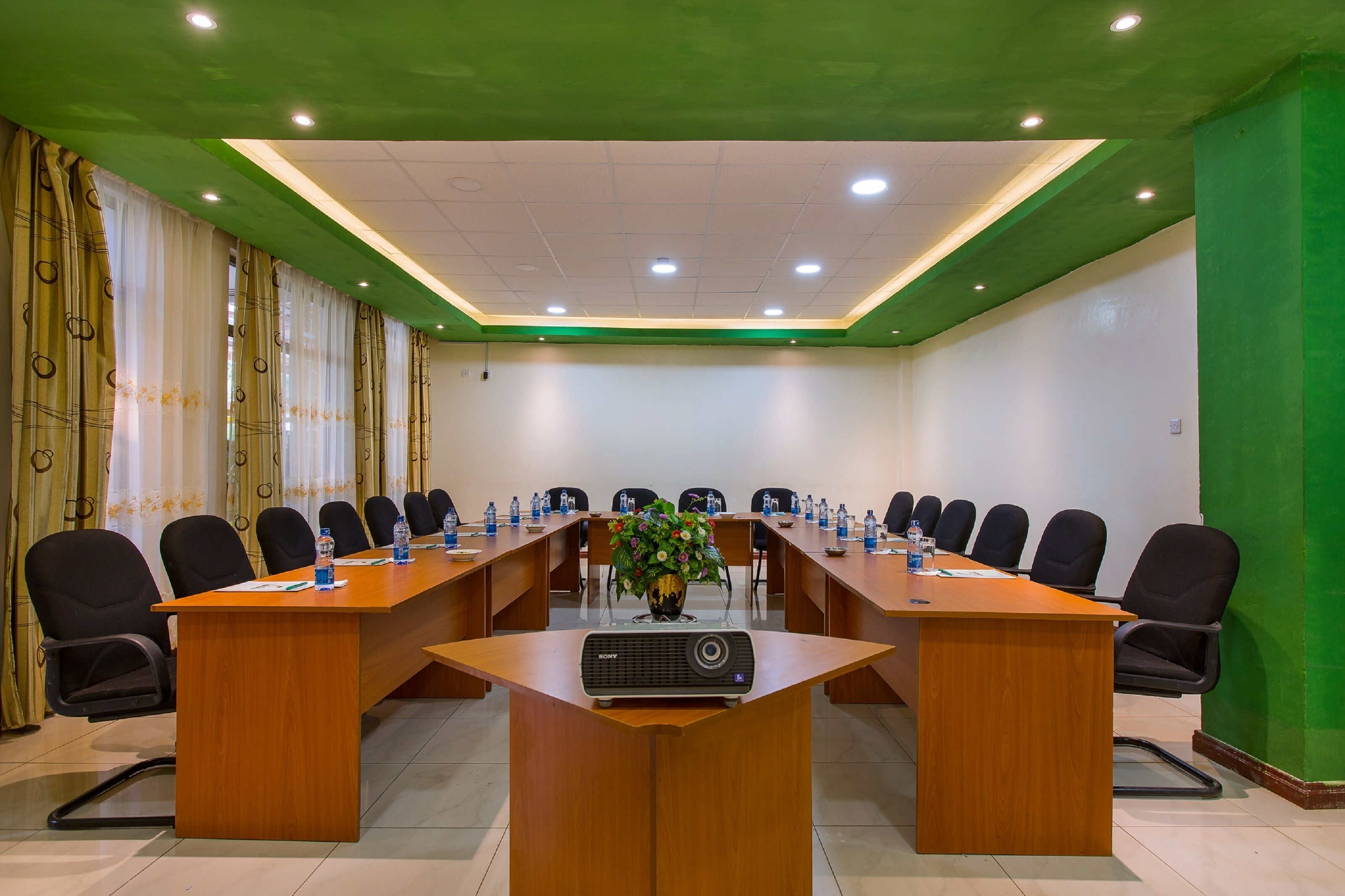 A conference room with a long table, black chairs, and a projector.