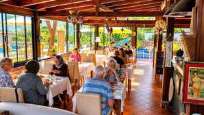 Un restaurante con terraza, vigas de madera y vistas a zonas verdes.