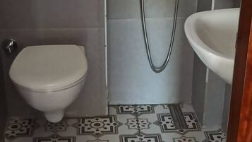 A bathroom with a toilet, a shower, and a sink.