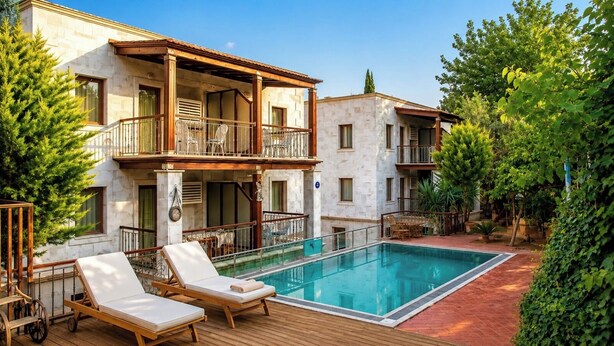 Un edificio de dos plantas con piscina, mobiliario exterior y jardín.