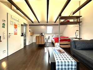 A compact room with a bed, a sofa, a desk, and a chair. There is a window with a view of the outside. - Schacht85 (Oberhausen)