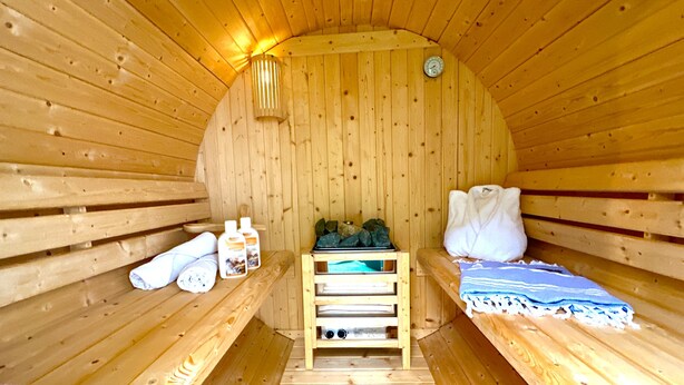 A wooden sauna with benches, towels, and a heater. - Schacht85 (Oberhausen)