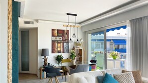 Un salon moderne avec un canapé, un coin repas avec une table et un balcon agrémenté de plantes.