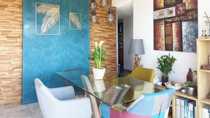 Un espace repas moderne avec une table en verre, des chaises contemporaines et un mur d’accent bleu.