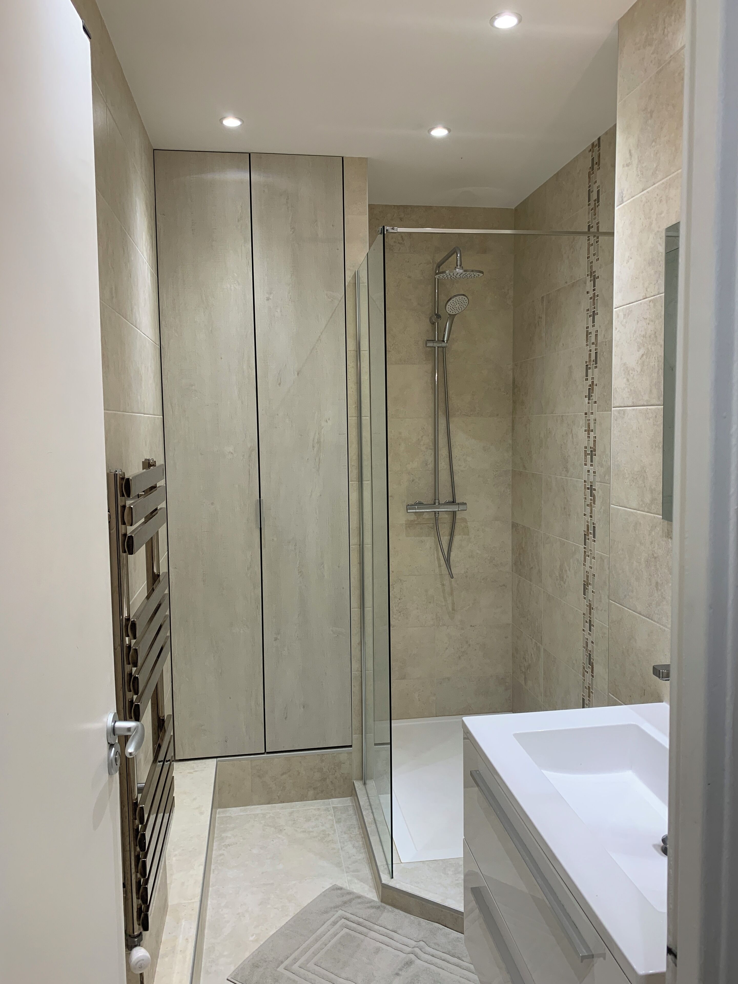 Un bagno moderno con doccia vetrata, vasca da bagno bianca e pavimento piastrellato.