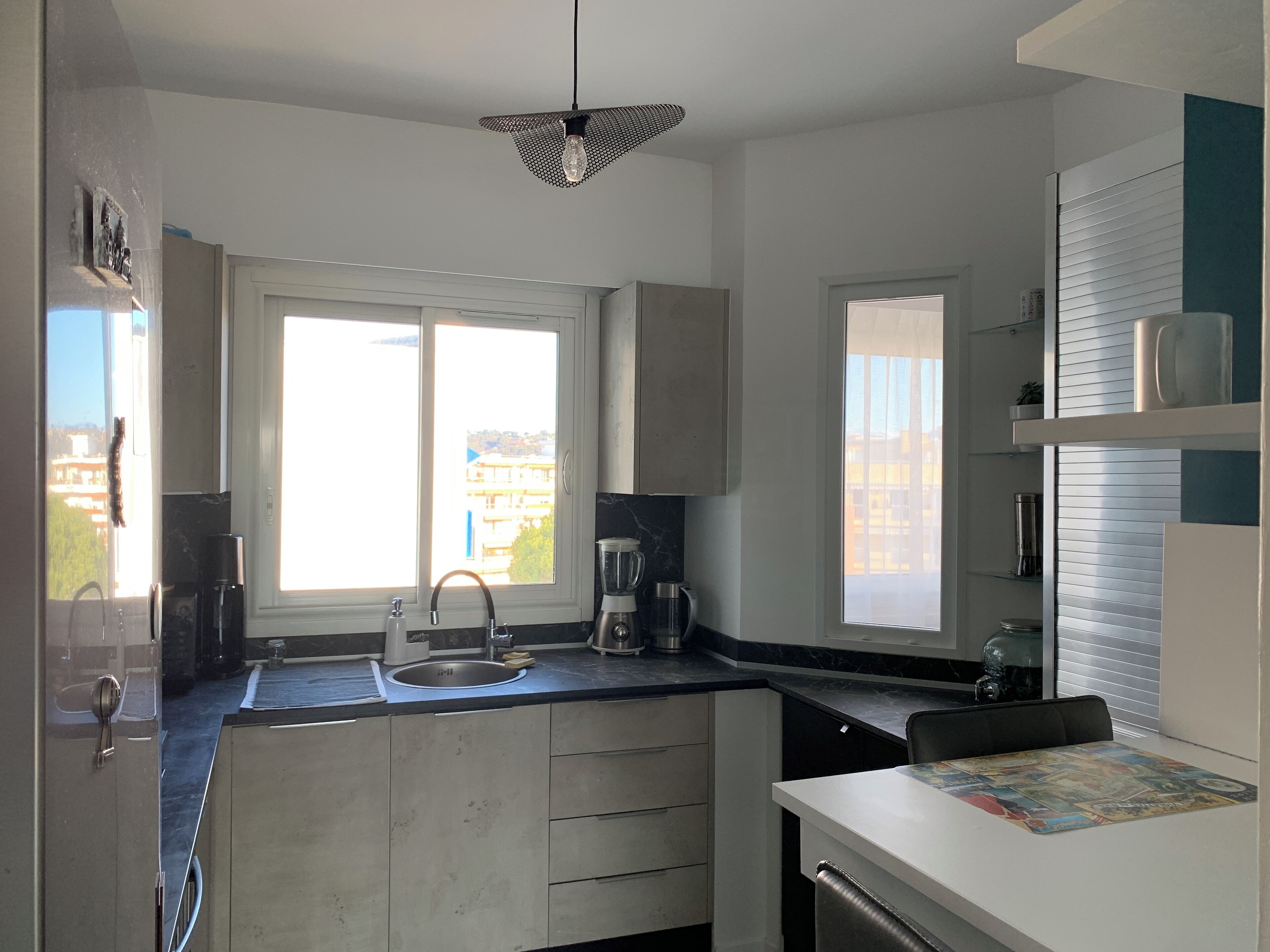 A modern kitchen with a large window, a sink, a blender, and a coffee maker.