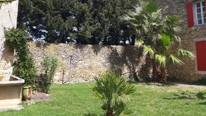 A stone wall, a palm tree, and a building with red shutters. - Apartment in a Provencal farmhouse in the Orange countryside (Orange)
