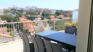 Un balcón con mesa y sillas, con vistas a una zona residencial con edificios y árboles.