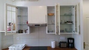 A kitchen with open cabinets displaying dishes, a toaster, and a coffee maker. - 2 rooms Full City Center, Clim WIFI Absolute Calm at 400 m Promenade des Anglai (Nice)