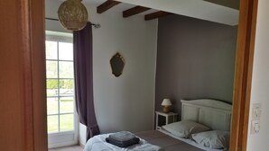 A bedroom with a bed, a nightstand, a lamp, and a window with curtains.