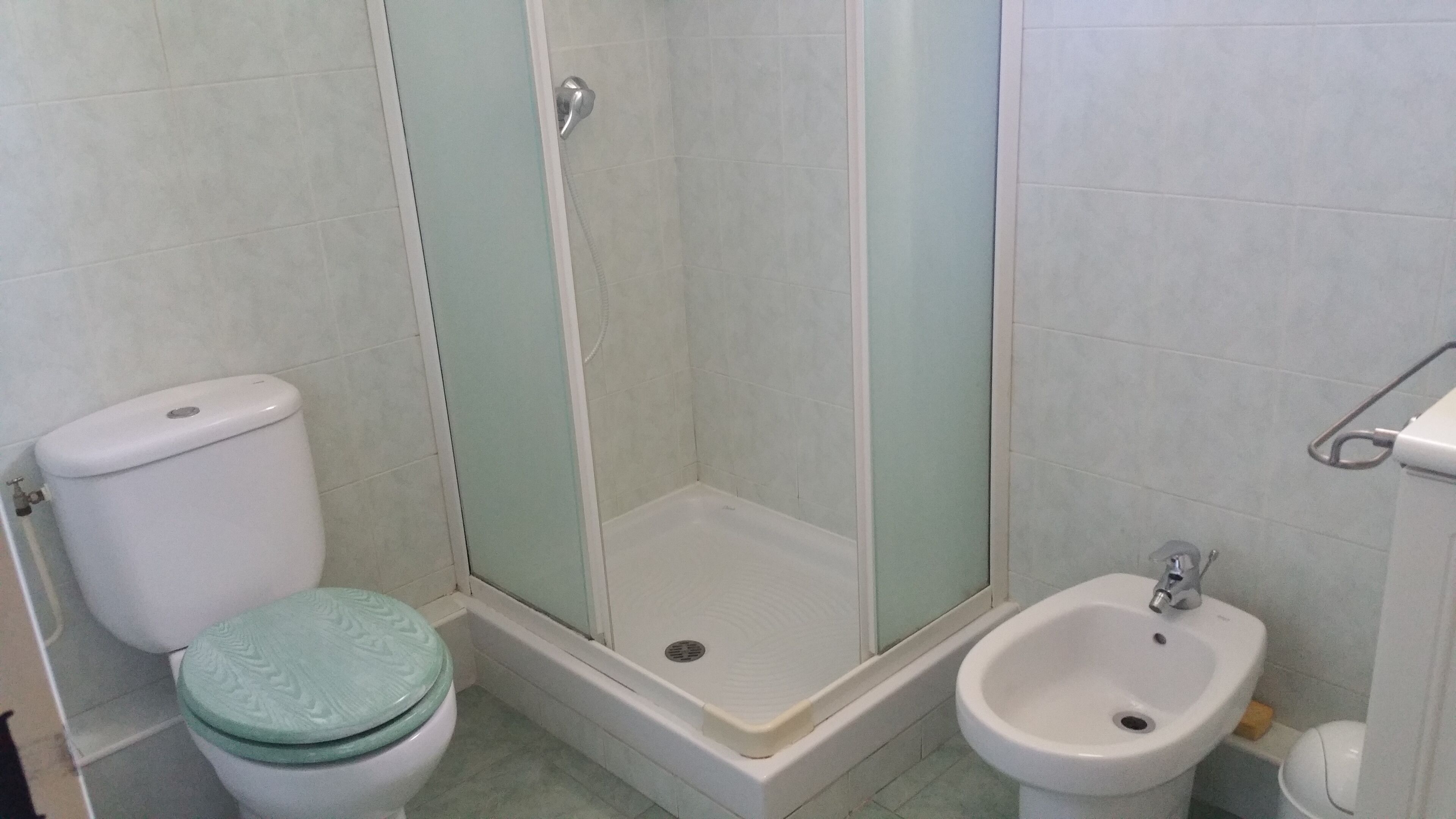 A bathroom with a toilet, a shower enclosure, and a bidet.
