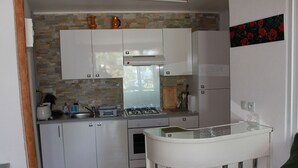 Una cocina moderna con armarios blancos, una estufa a gas y una pequeña isla con encimera de vidrio.