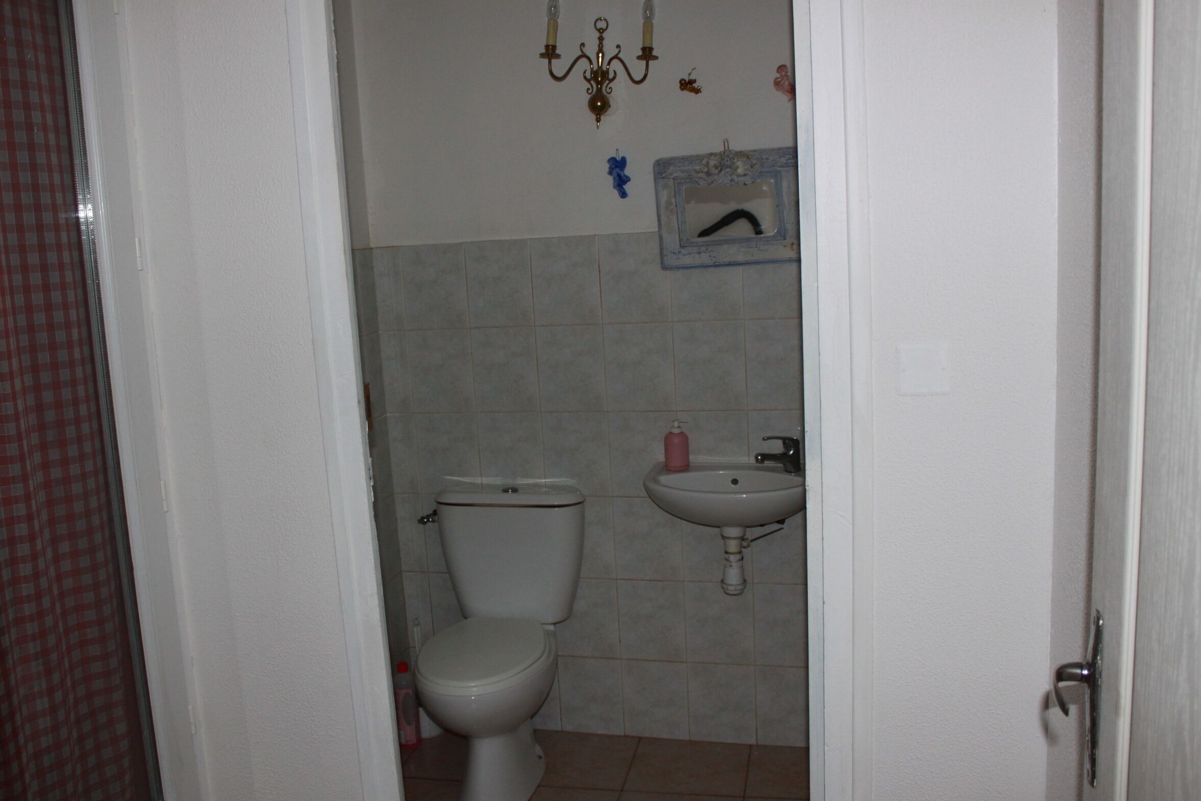A bathroom with a toilet, sink, and tiled walls.