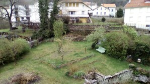 A residential area with houses, a grassy yard, and a stone wall.