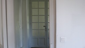 A hallway with a white door, a radiator, and a light switch on the wall.