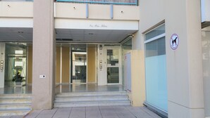 Una entrada de edificio con un letrero que dice "Les Pins Bleus" y un cartel de prohibido estacionar.