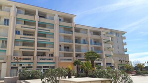 Un hotel de varios pisos con balcones, un patio central y abundante vegetación circundante.