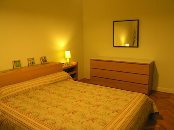 Une chambre à coucher avec un lit, une table de chevet, une commode et un miroir au mur.