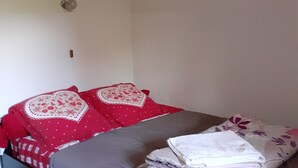 Une chambre à coucher avec un lit, des oreillers, une couverture, un petit objet décoratif sur le mur et un tableau.