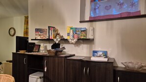 Une pièce comprenant un meuble en bois foncé, un panier en osier, une boîte blanche et une étagère avec des livres et des objets décoratifs.