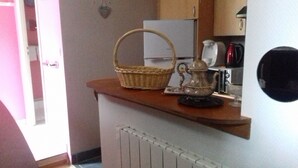 A kitchen counter with a wicker basket, a teapot, and a coffee maker.