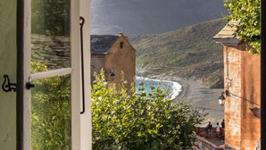 Une vue sur la côte, aperçue à travers une fenêtre ouverte, comprenant une plage, une tour et la végétation environnante.