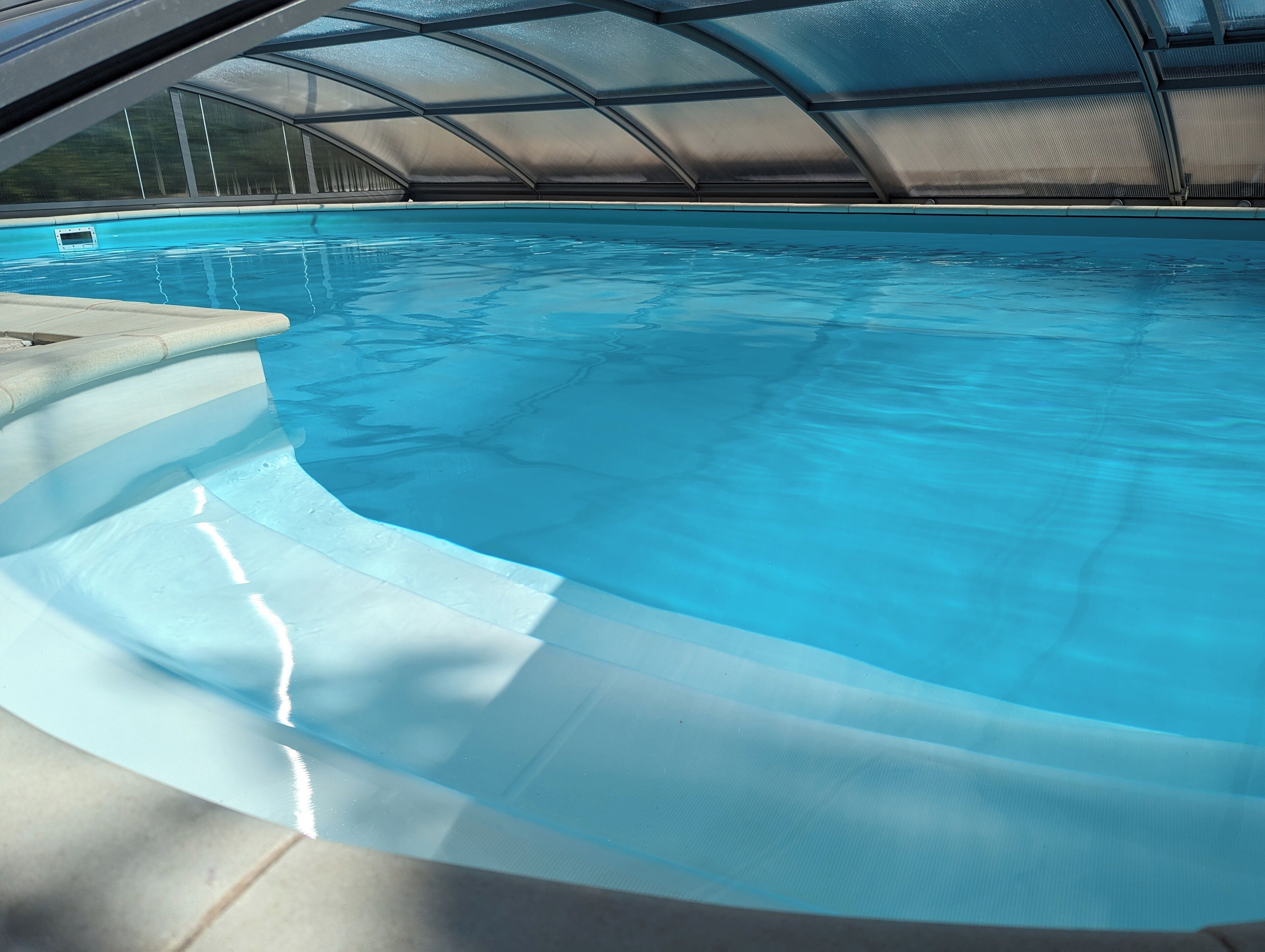 A swimming pool with a curved edge and a covered area.