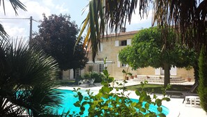 Ein Poolbereich mit klarem, blauem Pool, umgeben von Kübelpflanzen und Gartenmöbeln.