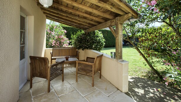 Eine überdachte Terrasse mit Holzmöbeln und einer weißen Laterne.