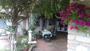 A patio with a table and chairs, surrounded by potted plants and flowers. - 'Villino flaminio - Your cottage at Rome in a park ! (Roma, Monte Caminetto)