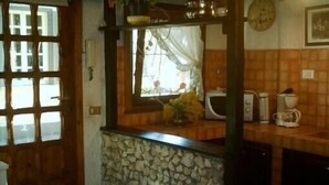 A kitchen with a stone backsplash, a microwave, and a coffee maker on the counter. - 'Villino flaminio - Your cottage at Rome in a park ! (Roma, Monte Caminetto)