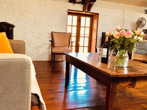 Relax in this charming room with a large table, comfortable chair, and beautiful vase with flowers.