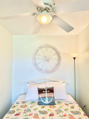 A bedroom with a bed, a wall clock, a ceiling fan, and a floor lamp. - Oceanside DUNESCAPE Studio•Direct Access to Secluded Beach•WiFi•Pool (Atlantic Beach)