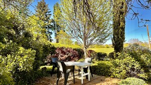 An outdoor patio with a table and chairs, surrounded by lush greenery and trees. - The small sheepfold in the Perigord (Villefranche-Du-Périgord)