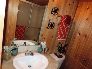 Une salle de bain rustique, avec des murs en bois, un lavabo blanc, un miroir et un porte-serviettes.
