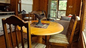 A wooden cabin interior with a dining table, chairs, a sofa, and a kitchen area. - Butterflies Cabin @ HomeAway Ranch (Boerne)