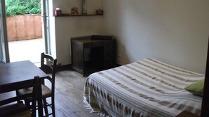 Een kleine, eenvoudig ingerichte kamer met een bed, een bureau en een stoel.