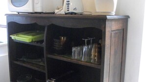 Een keuken met een magnetron, blender en koffiezetapparaat op een houten kast.