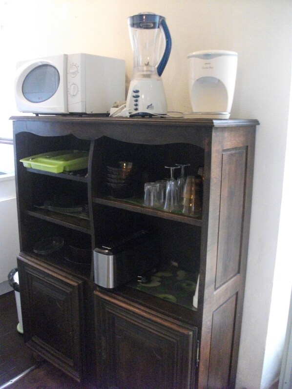 Una cocina con microondas, licuadora y cafetera sobre un mueble de madera.