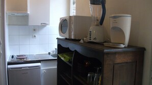 Een kleine keuken met een vaatwasser, een magnetron en een blender op een houten aanrecht.