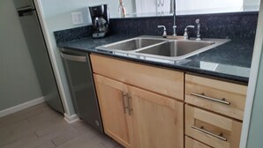 A kitchen with two sinks, wooden cabinets, a dishwasher, and a coffee maker. - Beautiful White Sand Gulf Beaches-Orange Beach, Alabama (Orange Beach)