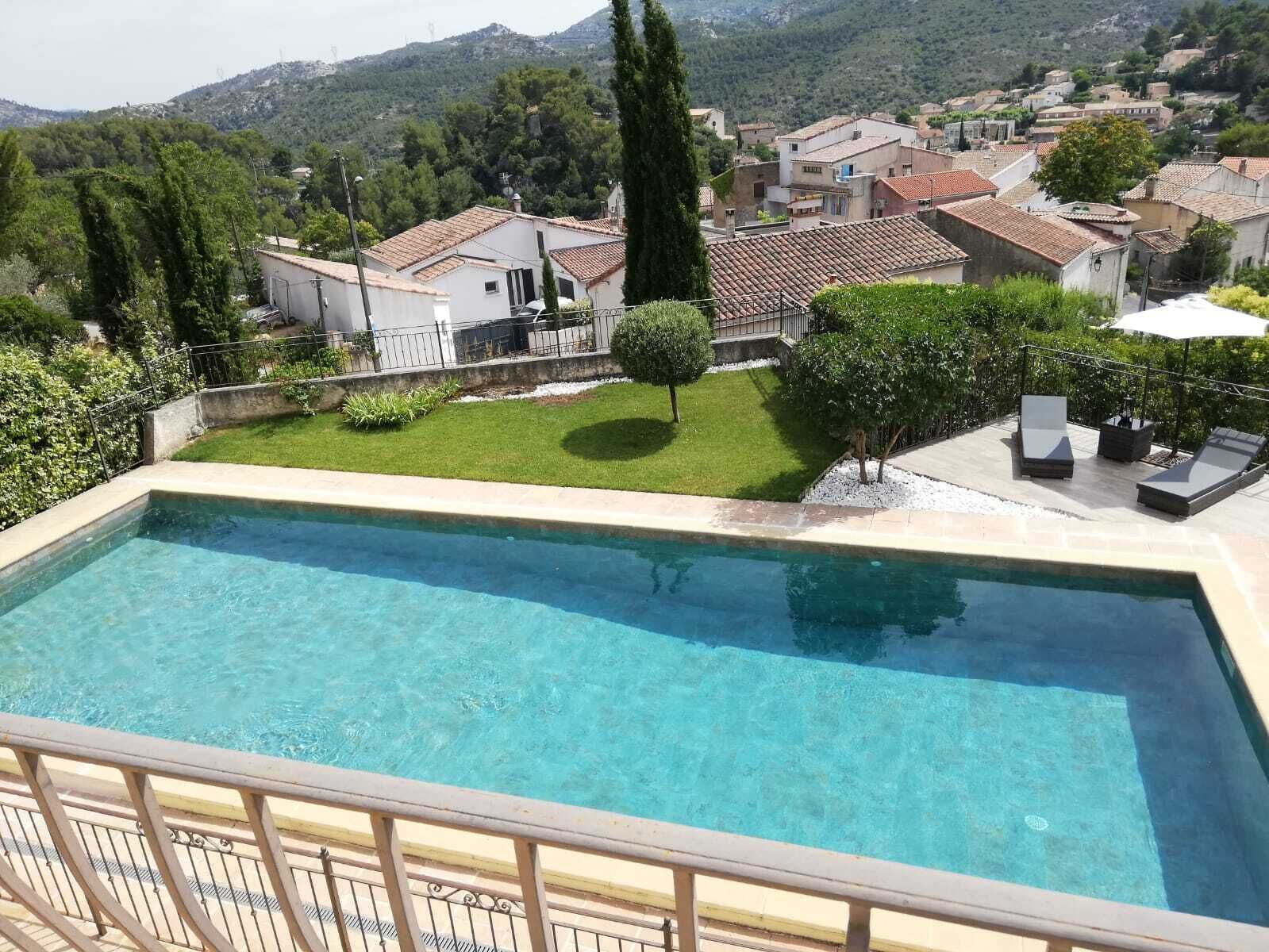 Una piscina con vistas a una zona residencial y colinas al fondo.