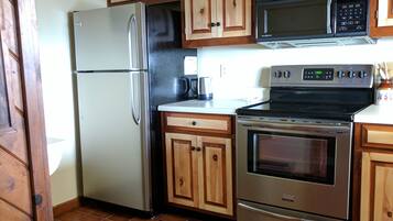 Una cucina con mobili in legno, un frigorifero in acciaio inossidabile, un forno a microonde e un forno.