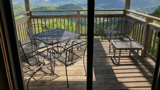A wooden deck with metal chairs and a table, overlooking a mountainous landscape. - Fantastic view! Condo located on the Crest of Sugar Mountain (Banner Elk)