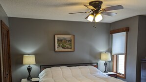 A bedroom with a bed, two bedside tables with lamps, a ceiling fan, a window with blinds, and a framed picture on the wall. - Fantastic view! Condo located on the Crest of Sugar Mountain (Banner Elk)
