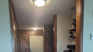 A hallway with wooden walls and a tiled floor leading to a kitchen area with wooden cabinets and a coffee maker. - Fantastic view! Condo located on the Crest of Sugar Mountain (Banner Elk)