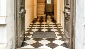Un couloir au sol à carreaux menant à un escalier.