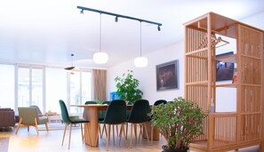 Un salon moderne avec un coin repas, de grandes fenêtres et une cloison en bois.